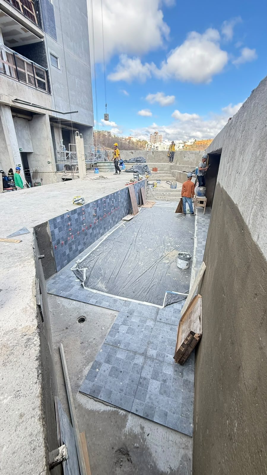 Execução de piso e revestimento em área externa do canteiro do Van Gogh Residencial, com manta impermeabilizante aplicada e operários no local