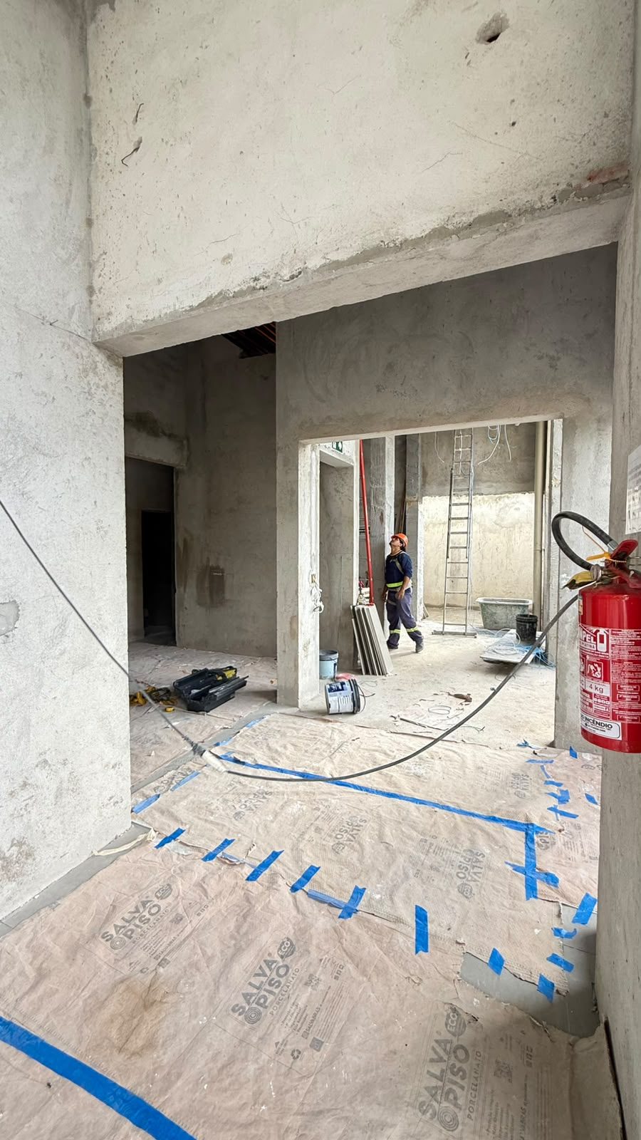 Ambiente interno do térreo do Van Gogh Residencial em fase de acabamento, com o piso protegido e operário trabalhando