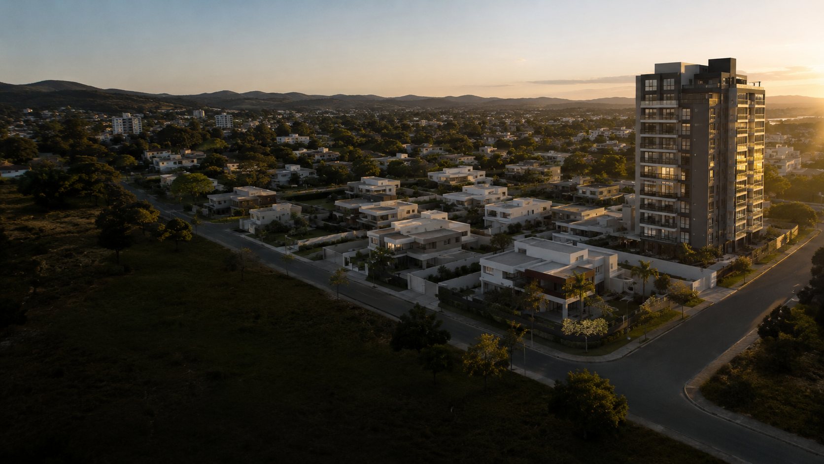 Vista aérea de bairro planejado em Governador Valadares, com condomínio de casas e torre residencial ao fim da tarde